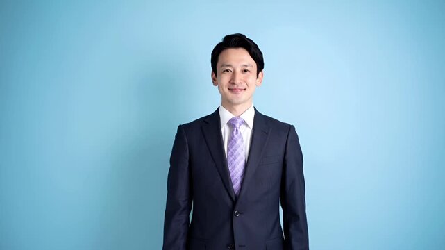 水色のシンプルな背景で撮影された、日本人ビジネスマンのポートレート映像。
ラベンダー柄のネクタイが、落ち着いた印象の中に柔らかさを加えています。
均一で柔らかな照明により、表情やスーツの質感が自然に強調。