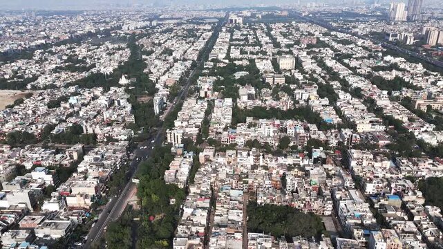 Expansive aerial panorama of Noida with endless housing clusters beneath a hazy afternoon sky, capturing rapid urban growth alongside persistent air pollution challenges.