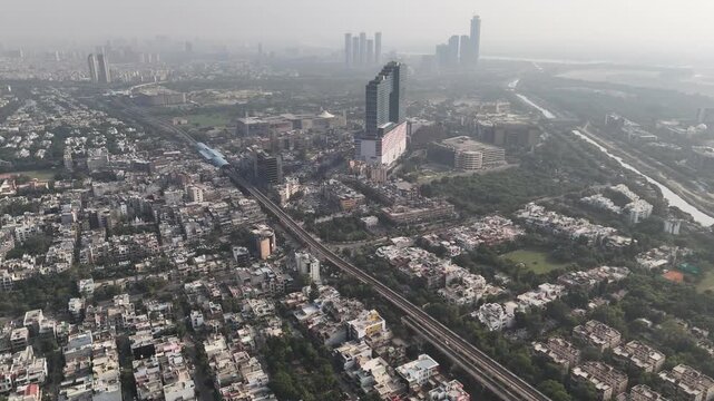 Aerial view of Noida Sector-18 showing dense urban sprawl and the elevated metro line under a visible haze, highlighting traffic congestion, rapid growth, and persistent air pollution in Delhi NCR.