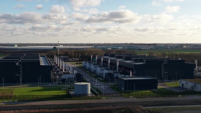 Aerial video of a large scale data center in The Netherlands, redundant computing infrastructure, emergency backup power generators, AI technology supporting big data processing and cloud services.