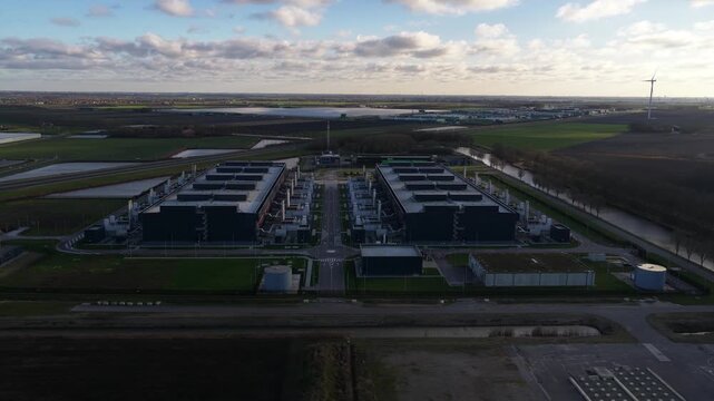 Aerial video of a large scale data center in The Netherlands, redundant computing infrastructure, emergency backup power generators, AI technology supporting big data processing and cloud services.