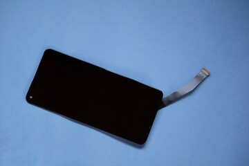 A smartphone LCD screen displayed without casing, revealing flexible ribbon cables and connector pins, highlighting delicate internal components, repair technology, electronics engineering