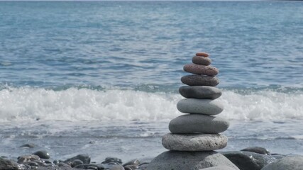 beach with cairn rocks, zen-like pebbles stacked in balanced pyramid against ocean waves, Balanced stones on beach, Meditation and mindfulness, harmony, travel, and serenity coastal retreats
