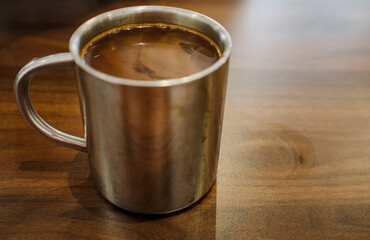 Traditional Malaysian coffee in vintage stainless steel cup on wooden table with copy space