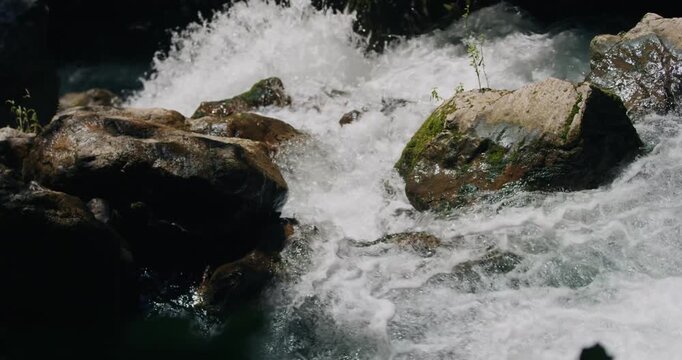 Slow motion unveils shimmering mist draping textured moss outcrops as water bursts over eroded stone in &Ouml;tschergr&auml;ben's chasm, capturing turbulent water texture amid primal canyon flow, Austria.