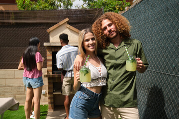 Group of friends having fun at barbecue party, drinking lemonade in the backyard