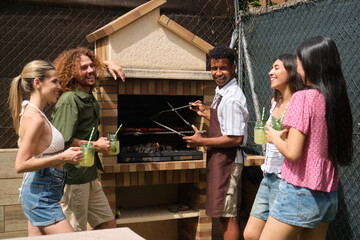 Happy friends enjoying a barbecue party, grilling meat and drinking lemonade in backyard