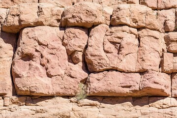 Rough-hewn red rock wall, blocky, layered, and slightly weathered