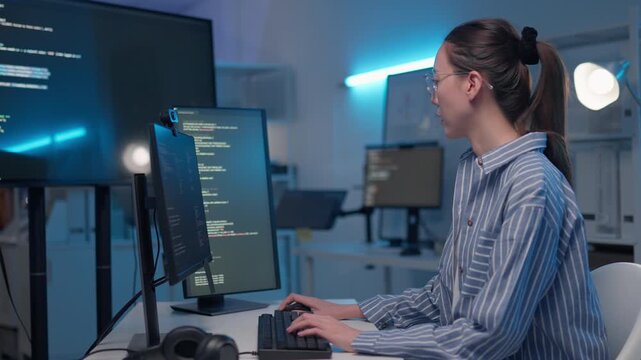 Professional Asian woman software developer coding on multiple monitors in workspace. Female software engineer writing scripts and developing software. cyber security and programming concept.