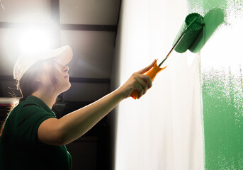 Young women painting a wall with paint roller