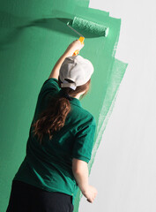 Young women painting a wall with paint roller
