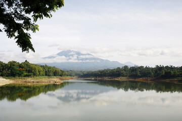 Serene Lake Lahor with Majestic Mount Kawi View: Lush Forest, Calm Water & Cloudy Sky, East Java