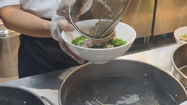 Close up of Chef Prep Pho shows fresh meat in strainer. Expert Chef Prep Pho is important part of cooking soup. Professional Chef Prep Pho ensures high quality of authentic vietnamese cuisine.