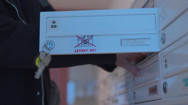 A man unlocks a mailbox and takes out his mail - closeup