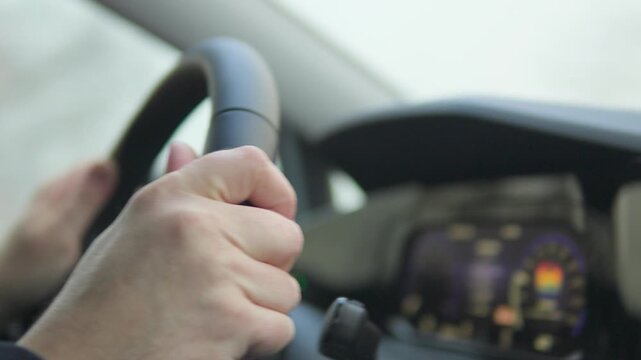 Closeup on man's hands on a steering wheel as he drives a car