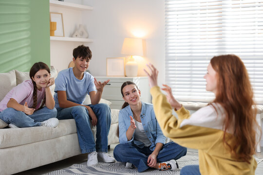Group of teenagers playing charades game at home