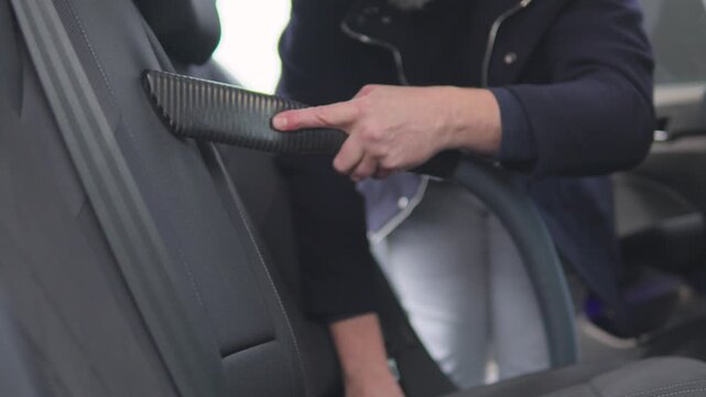 A handsome middle-aged man vacuums the backseat in his car
