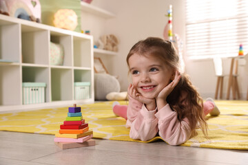 Happy little girl lying on floor in playroom