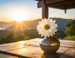 Daisy flower in vase on wooden table with sunset view and mountain range