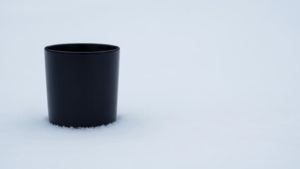 Black cup on snowy surface in winter landscape