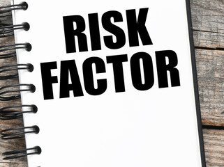 RISK FACTOR words written in an office notebook.