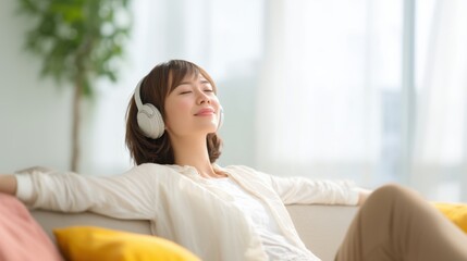 Young woman with headphones relaxing on a couch in a bright living room, enjoying music and peaceful ambiance, embodying tranquility and self-care in a modern home environment