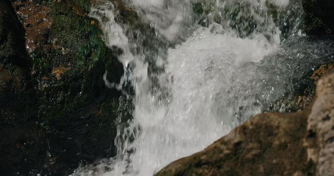Slow motion close-up reveals turbulent white foam exploding over moss-covered boulders in &Ouml;tschergr&auml;ben gorge, capturing dynamic water texture amid shamanic waterfall site near Mirafall.