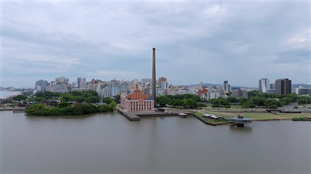Usina do Gasometro and Porto Alegre cityscape with CAFF reveal under overcast sky. Captured in aerial forward approach with right turn. Recorded in 10-bit D-Log 4K professional video quality.
