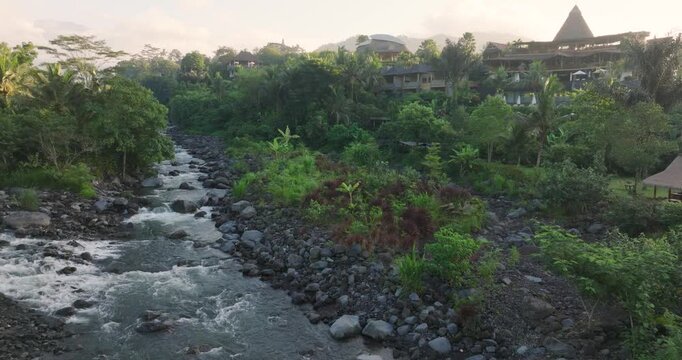 4K drone footage of lush Sidemen, Bali at sunrise, flying low over river valley, jungle, and rice fields, capturing serene tropical nature and rural Indonesian landscape