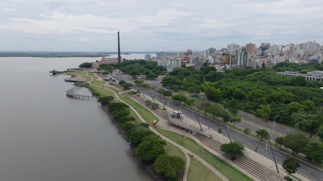 Usina do Gasometro, waterfront and Parque Marinha captured in slow motion aerial high angle view in Porto Alegre. Features urban park and skyline. Recorded in 10-bit D-Log 4K video.