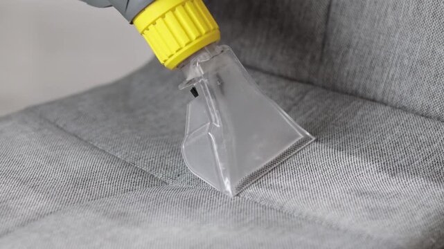 Deep cleaning of a fabric chair using a carpet and upholstery cleaner. Removing dirt and stains from upholstered furniture at home. Close up.
