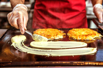 Chef Cooking Pancakes on Hot Griddle with Spatula in Kitchen