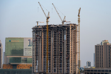 Fototapeta premium High-Rise Residential Tower Under Construction with Cranes in Abu Dhabi