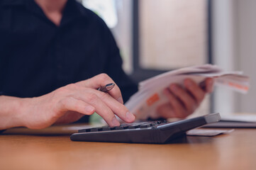 Close up hand using calculator to calculate home finance, accounting budget management, monthly expenses, checking bills, taxes, bank account balance and calculating expenses.