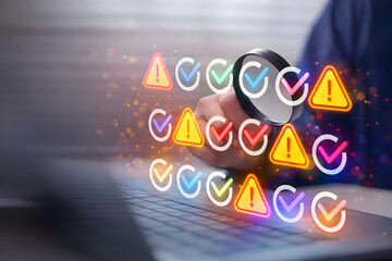 Hand using magnifying glass to inspect warning and check icons on laptop screen, representing system monitoring, debugging, error detection, and cybersecurity analysis