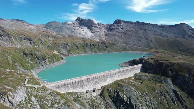 Aerial view of Diga del Goillet lake, a stunning turquoise expanse contrasting with the rugged, mountainous terrain surrounding it, Diga del Goillet, Valle d'Aosta, Italy.