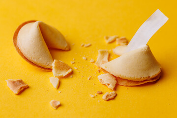Fortune cookies on an intense yellow background with shadows for conceptual imagery about finding answers and traditional Asian luck.