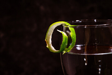 Cocktail glass with lime peel garnish on the rim of the glass
