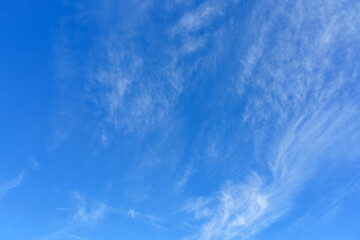 Clear blue sky with light clouds during daytime over a sunny landscape in early afternoon