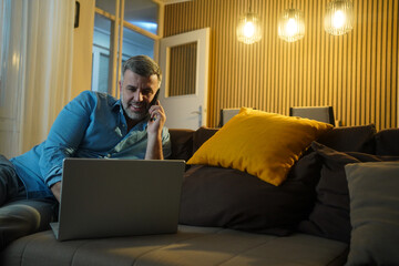 Man on a phone call with laptop at home for remote work, happy with technology