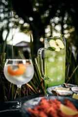 Mixed cocktail drinks and sangria with snacks on restaurant table outdoors at sunset