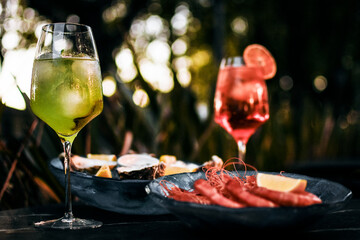 Mixed cocktail drinks and sangria with snacks on restaurant table outdoors at sunset
