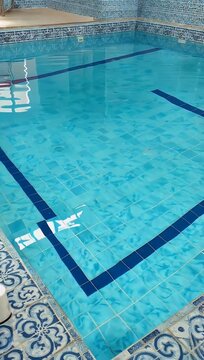 Refreshing 4K pool water surface background showing blue mosaic square tiles beneath shimmering clear water 