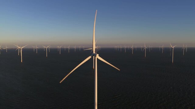 Aerial view of numerous wind turbines standing tall in the sea, their white blades contrasting against the dark water, Breezanddijk, Friesland, Netherlands.