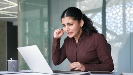 Happy businesswoman watching sports match or competition using laptop sitting at workplace in business office. Young female celebrating success showing excitement and achievement.