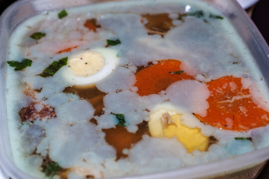 Homemade Aspic Jelly with Meat, Boiled Eggs and Carrots in a Plastic Container, Traditional Slavic Cuisine, Holodets or Studen Dish Close-up