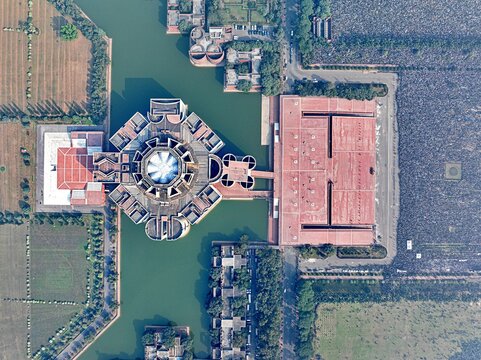 Dhaka, Bangladesh - 31 December 2025: Aerial view of Jatiya Sangsad Bhaban standing as a monumental island amidst a tranquil lake, its geometric forms casting shadows on the water.