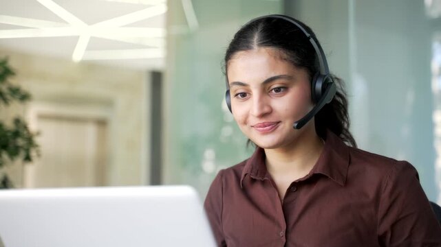 Smiling woman customer support representative, corporate operator in headset working on helpline telesale talking using laptop in business office. Agent of call center advises clients online. Close up