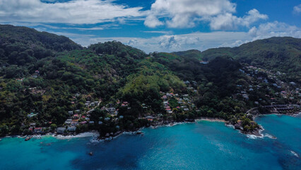 Obraz premium Elevated Aerial View of Residential Village Nestled on Steep Green Hills Overlooking the Ocean