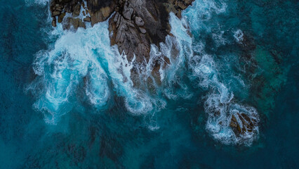 Coastal Pattern: Dark Boulders, White Foam, and Muted Teal Water Next to Island Villa © Bozophy